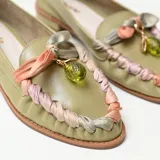 Mocasines de cuero color verde pistacho con taco bajo y punta redondeada. Presentan detalles artesanales de tiras entrelazadas en tonos pastel y un aplique colgante con cuenta translúcida en el empeine.
