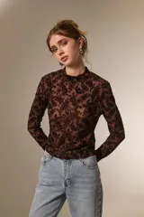 Top de manga larga con cuello alto, confeccionado en tejido semitransparente con estampado tipo paisley en relieve.