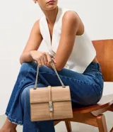 Cartera tipo shoulder bag de tamaño mediano, confeccionada en poliuretano con textura efecto croco. Presenta una tapa frontal con cierre metálico de giro, asa de mano reforzada y una correa larga de cadena plateada. Diseño estructurado con acabado sofisticado.