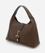 Bolso de hombro tipo hobo mediano, color marrón oscuro, con textura de cuero granulado. Presenta un cierre frontal decorativo de herradura metálica dorada sobre una solapa. Incluye una correa de hombro ancha y un neceser interior.