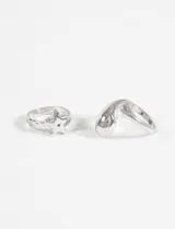 Set de dos anillos plateados de zinc, uno con aplique de estrella y otro con forma geométrica.