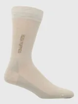 Calcetín de vestir de caña media color beige claro, con banda elástica superior de punto acanalado en color crema. Presenta el logo "Hush Puppies" bordado en color marrón en la caña.