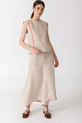Falda midi de lino color beige, de corte evasé con bolsillos delanteros, cierre de botón y trabillas para cinto.