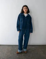 Jean de estilo recto y tiro medio-bajo confeccionado en denim azul marino oscuro. Presenta un diseño con costura vertical en la parte posterior de las piernas y bolsillos traseros clásicos. Esta prenda está elaborada con algodón reciclado bajo procesos de producción sostenible.