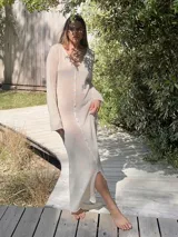 Vestido largo color crudo, de tejido de algodón fino y ligero, con escote en V y mangas largas acampanadas. Se puede usar con el escote hacia adelante o hacia atrás.