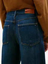 Jean de corte amplio y estilo barril con talle medio. Presenta un diseño de cinco bolsillos, cierre de cremallera con botón y un acabado con efecto desgastado en caderas y rodillas.