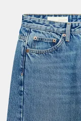 Jeans de tiro medio con diseño wide leg y pernera ancha, estilo de cinco bolsillos, cierre frontal con cremallera y botón metálico.