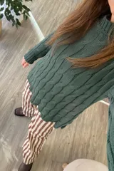 Sweater tejido verde con cuello alto y diseño de trenzas.