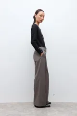 Pantalón sastrero de corte recto y tiro alto, confeccionado en tela con textura melange en tono beige. Presenta cierre frontal con botón y bolsillos laterales.