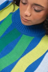 Buzo de tejido de punto con diseño de rayas verticales onduladas en tonos azul, verde, lima y celeste. Presenta cuello redondo y puños acanalados.
