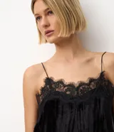 Blusa de terciopelo negro con breteles finos y escote decorado con encaje delicado. Presenta un corte fluido y elegante.