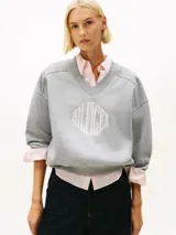 Buzo gris de felpa con cuello en V, corte amplio, puños y bajo de punto canalé. Cuenta con un logo bordado de estilo universitario en el pecho.