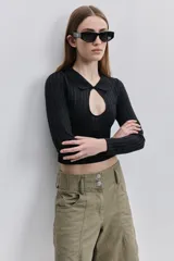 Top de calce al cuerpo color negro, confeccionado en tejido elástico con textura acanalada, con cuello camisero, mangas largas y recorte frontal tipo cut-out.