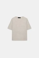 Jersey de punto color beige, confeccionado en lana 100%, con cuello redondo y manga corta.