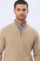 Buzo tejido liso de algodón color beige, con cuello alto, cierre frontal parcial y detalle de tirador en cuero.