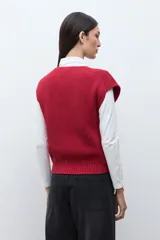 Chaleco tejido de punto acanalado en color rojo, con cuello redondo y cierre frontal de botones oscuros.