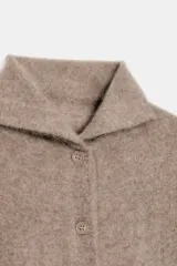Chaqueta de punto confeccionada en lana, con cuello subido, manga larga y cierre frontal con botones. Presenta un acabado con efecto cepillado.