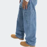 Pantalón cargo de denim negro con corte holgado, bolsillos laterales tipo cargo y cierre frontal con botón y cremallera.