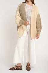 Cardigan de punto grueso con diseño color block en tonos beige, crema y verde oliva. Corte oversize y mangas largas.