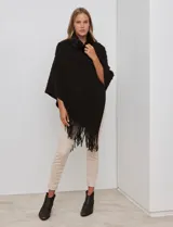 Poncho tejido negro con textura, cuello alto de velour negro y terminación con flecos largos en el ruedo.