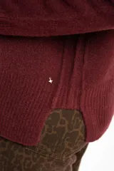Sweater de tejido de punto color bordó, con cuello redondo, mangas largas y puños acanalados. Presenta un diseño de corte recto y textura suave.