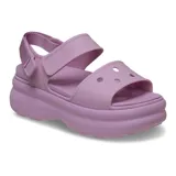 Sandalia negra de plataforma con suela gruesa y texturizada. Presenta una tira ancha sobre el empeine y una correa ajustable en el talón con cierre de velcro.