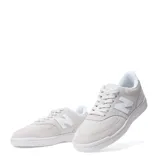 Championes urbanos New Balance modelo 080, color gris claro con detalles en blanco. Presentan el logo 'N' característico en los laterales, confeccionados en una combinación de gamuza y malla, con suela de goma blanca.