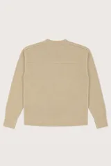 Buzo de punto color beige, con cuello redondo, mangas largas y diseño con aberturas laterales en el ruedo.