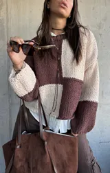 Sweater de punto con diseño de bloques de color en tonos chocolate y beige, de corte holgado y mangas largas con puños ajustados.