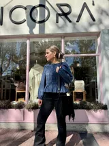 Blusa de manga larga con cuerpo fruncido mediante elásticos y terminación con volados en el ruedo. Presenta un diseño versátil y adaptable.