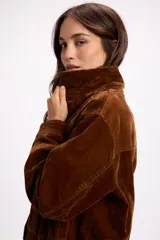 Campera de terciopelo color marrón chocolate, con cierre frontal, bolsillos laterales y elástico en el ruedo. Presenta un diseño de corte holgado con costuras marcadas.
