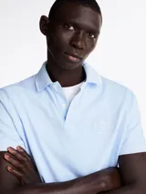 Chomba celeste de algodón orgánico y elastano, de corte regular, con cuello de chomba, cartera de 2 botones y logo gráfico de Tommy Hilfiger bordado en el pecho.