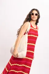 Vestido largo de tejido de punto con diseño de rayas en zigzag de colores rojo, fucsia y amarillo. Presenta cuello redondo y diseño sin mangas.
