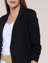 Blazer sastrero liviano de crepé flexible color negro, de silueta semi holgada, corte recto y caída abierta sin botones. Presenta cuello con solapa clásica en muesca delgada y mangas tres cuartos fruncidas.