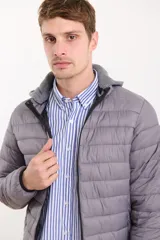 Campera capitoneada color azul marino, con capucha de algodón gris desmontable y cierre frontal. Tiene dos bolsillos exteriores con cierre.