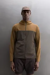 Chaqueta cortavientos Zara Athleticz de diseño bicolor en tonos marrón y tostado, con capucha, cierre frontal de cremallera y bolsillos funcionales.