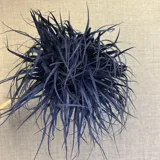 Broche decorativo de tela azul marino, con forma de esfera o flor abstracta, compuesto por tiras finas de material textil que se extienden en todas direcciones.