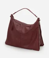 Bolso hobo grande de poliuretano color bordó, de diseño desestructurado con asas dobles y cierres laterales ajustables con tiradores. Cuenta con cierre superior y herrajes metálicos plateados.