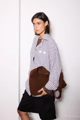 Camisa de corte oversize con estampado de cuadros en tonos azules y rosados. Presenta cuello clásico, cierre frontal con botones y detalle de estrellas blancas estampadas en el pecho.