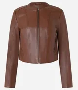 Campera básica de cuero sintético (PU) color marrón oscuro, con cuello redondo, cierre frontal y recortes decorativos. Cuenta con mangas largas y bolsillos con cierre.