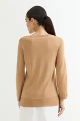 Sweater rosado de tejido de punto con escote en V y mangas largas con puños acanalados. El ruedo también es acanalado y presenta un detalle de crochet.