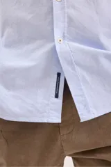 Camisa blanca de manga larga con cuello clásico y cierre frontal con botones.