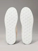 Zapatillas de corte bajo Calvin Klein Jeans en color beige, confeccionadas en una combinación de ante y piel nobuck. Presentan un diseño minimalista con suela cupsole blanca, detalle de trabilla trasera en color marrón y forro interior en contraste negro. Incluye el logo de la marca grabado en el lateral y en la mediasuela.