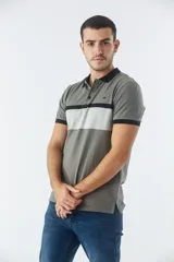 Remera tipo polo de manga corta con diseño de bloques de color en tonos verde oliva, gris y negro. Presenta cuello y puños a contratono, cierre frontal con botones y logo bordado en el pecho.