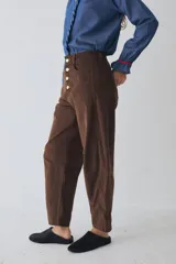 Pantalón de corte barrel en pana color azul marino, con cierre frontal de botones metálicos dorados a la vista y costuras reforzadas en las rodillas.