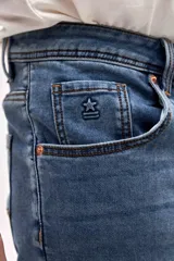 Jean de corte slim, ajustado desde la cadera hasta los tobillos, en color azul medio con acabado clásico.