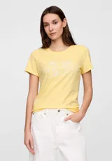 Remera de algodón color amarillo con cuello redondo y mangas cortas. Presenta el logo de la marca estampado en el frente con un diseño floral lineal en color blanco.