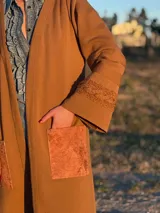 Saco largo color marrón, tejido en lana con trenzas tejidas y bolsillos de cuero.