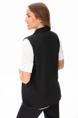 Chaleco negro sin mangas con solapas y cierre con un botón.