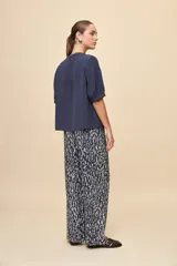 Blusa de manga corta color negro, con calce relajado, escote redondo con abertura y lazo para anudar. Presenta detalles de tablas horizontales en la parte superior que aportan textura al diseño.